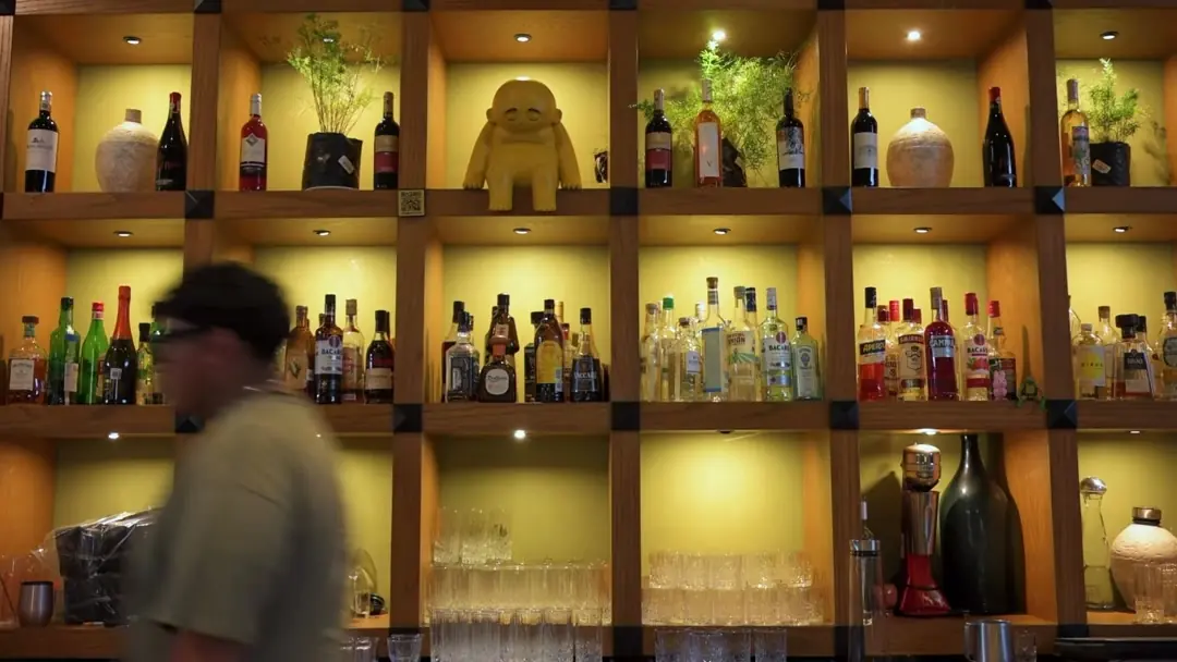 La barra de Los Arbolitos de noche: estantería de madera en retícula con nichos iluminados en ámbar, vinos y destilados.