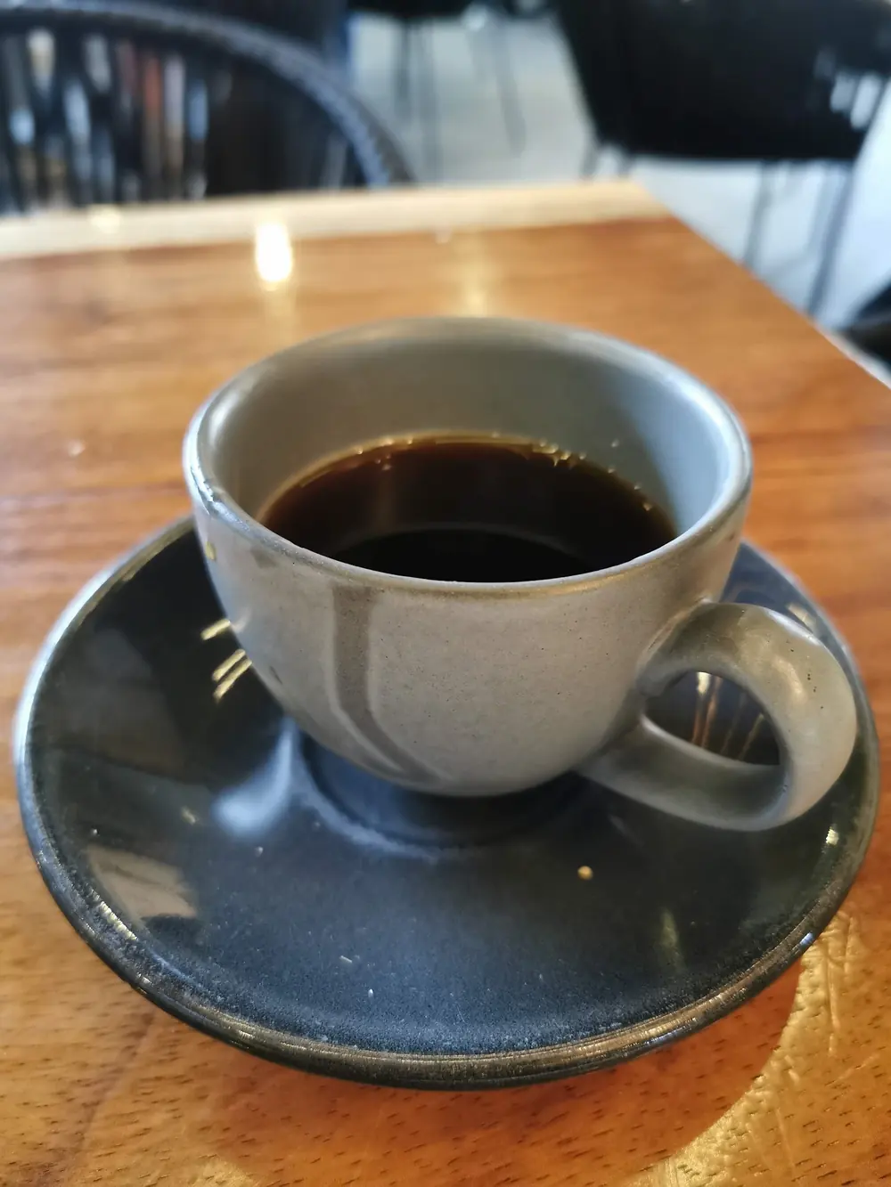 Taza de café sobre plato, en una mesa de madera.
