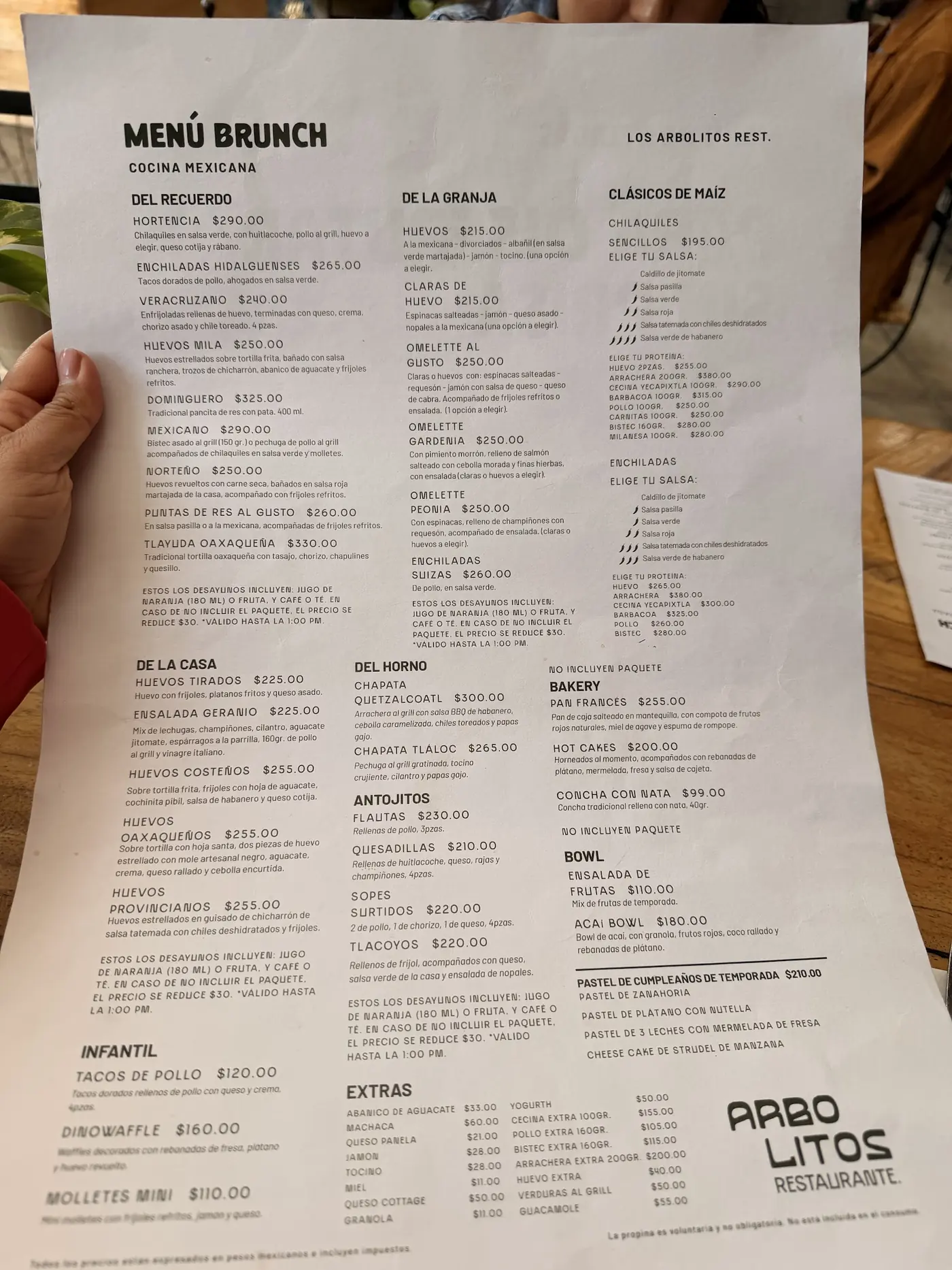 La carta impresa de Los Arbolitos sostenida en la mano, con las secciones Del recuerdo, De la casa y Clásicos de maíz.